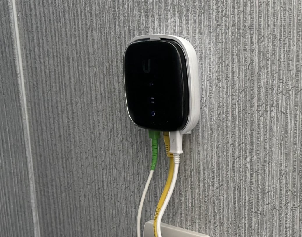 A small white fibre ONT installed on a windowsill inside a home.